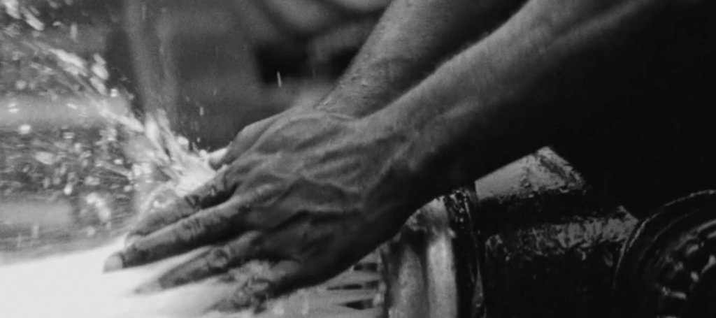B&W thumbnail of two hands touching water at open fire hydrant. Source: Nas' music video "Ugly."