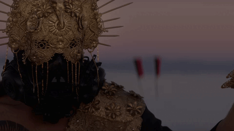 "A person with golden accessories and a golden helmet looking straight ahead" from A Thousand Suns