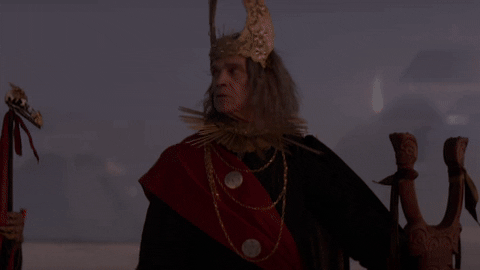 "A man wearing a crown standing in front of futuristic pyramids looks around when the lights change" from A Thousand Suns